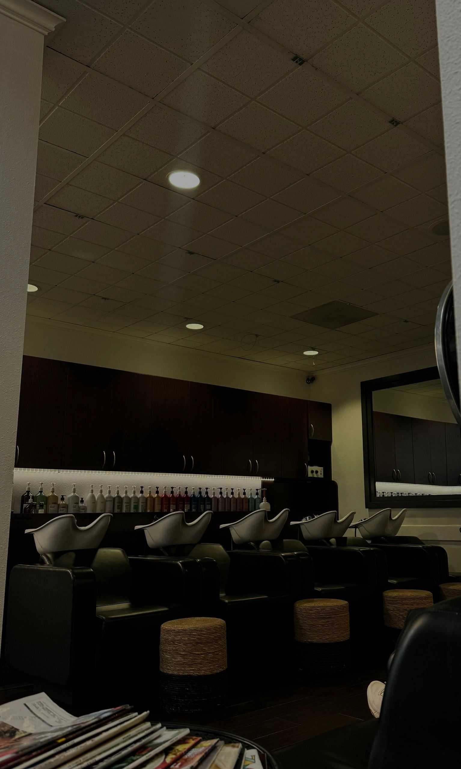 Modern hair salon with shampoo stations and products on shelves.